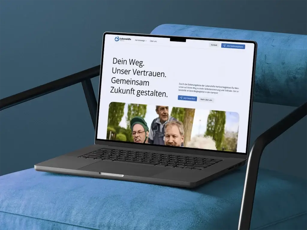 Ansicht der Homepage von der Karriereseite der Lebenshilfe- Herford. Das Notebook steht auf einem farblich angepassten Sessel in Blau.